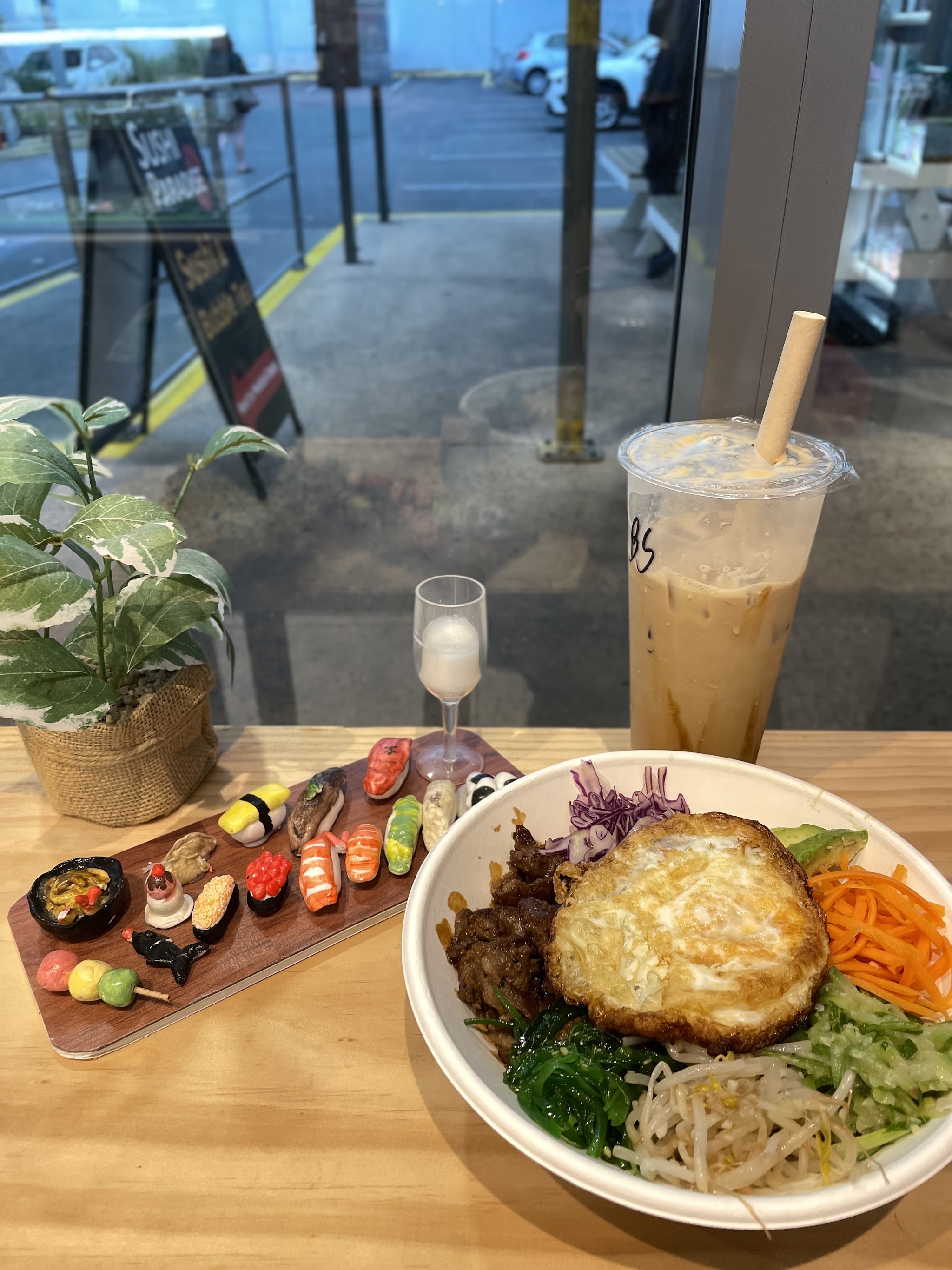 A rice bowl by the window with the Sushi Paradise sign outside